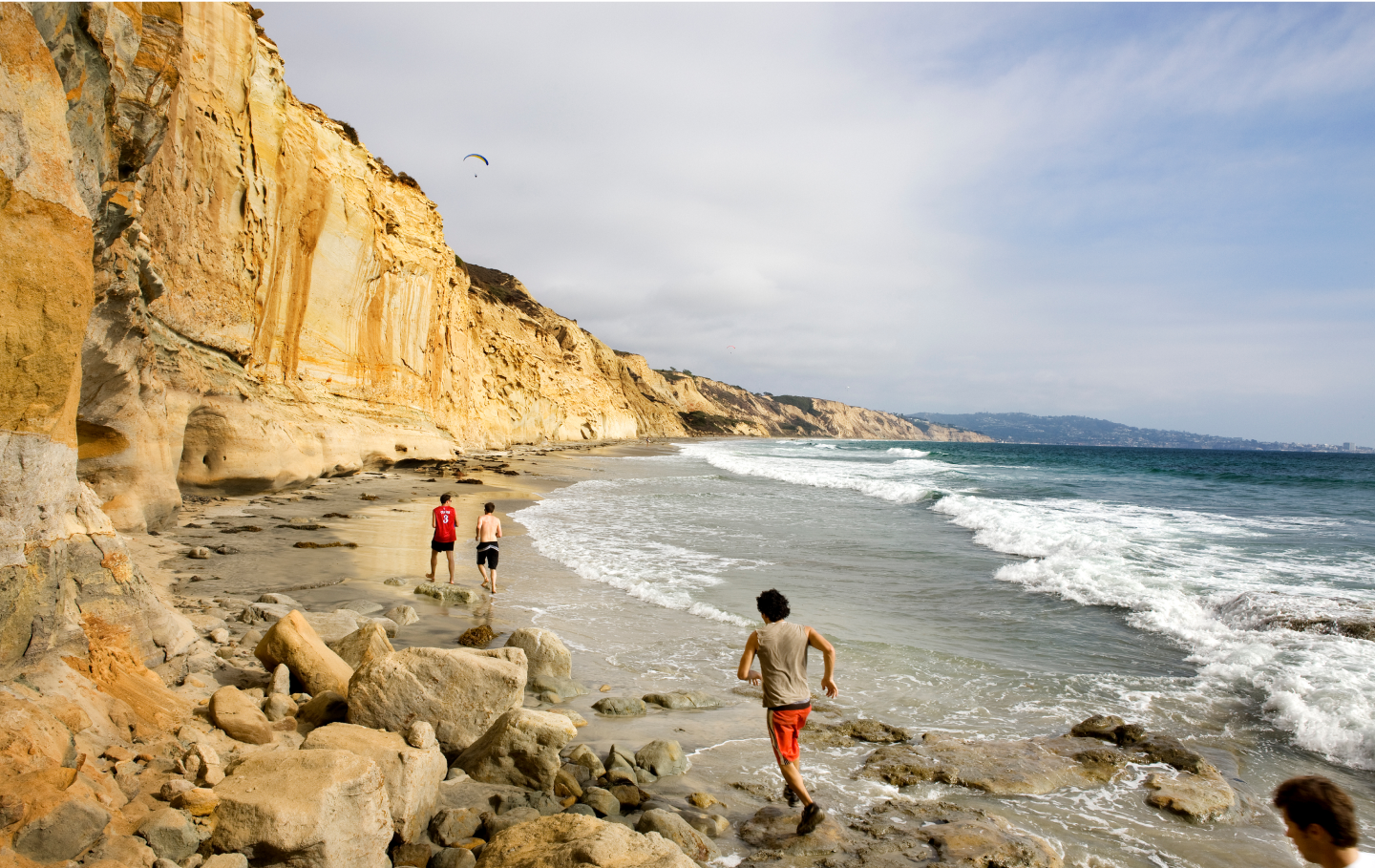 People running on a cliff beach